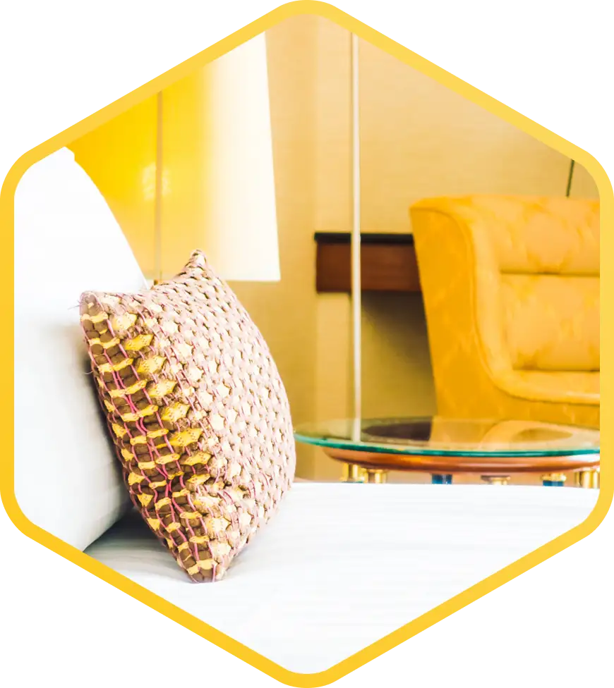 Beyaz nevresim takımları, başucu lambası ve çiçek motifli dekoruyla parlak sarı yatak odası, sade ve modern bir görünüm yaratıyor.